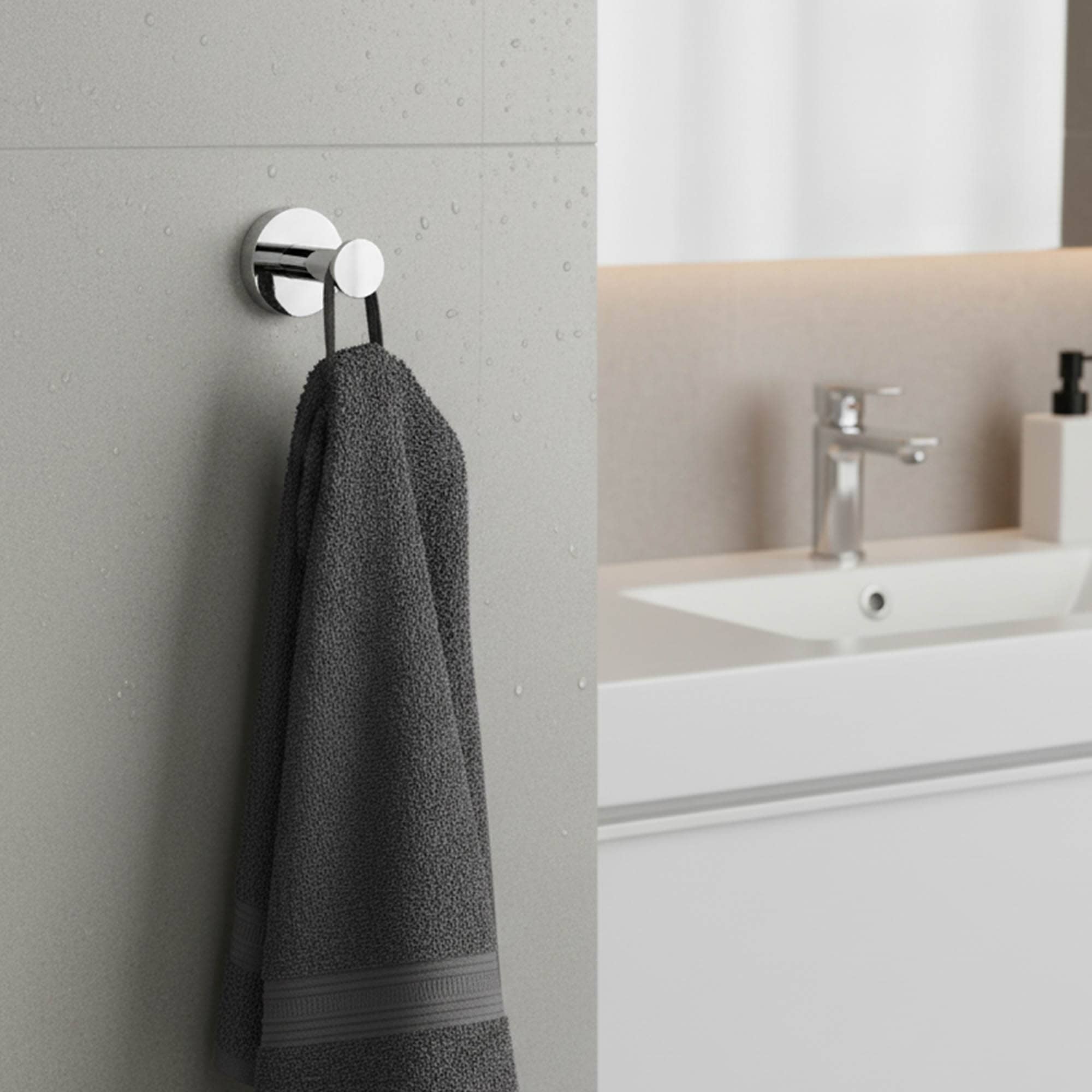 "Chrome robe hook with dark gray towel on wet tile wall beside modern white vanity"