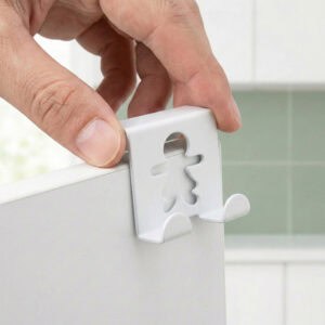 "Close-up of hand placing white gingerbread figure hook over cabinet edge"