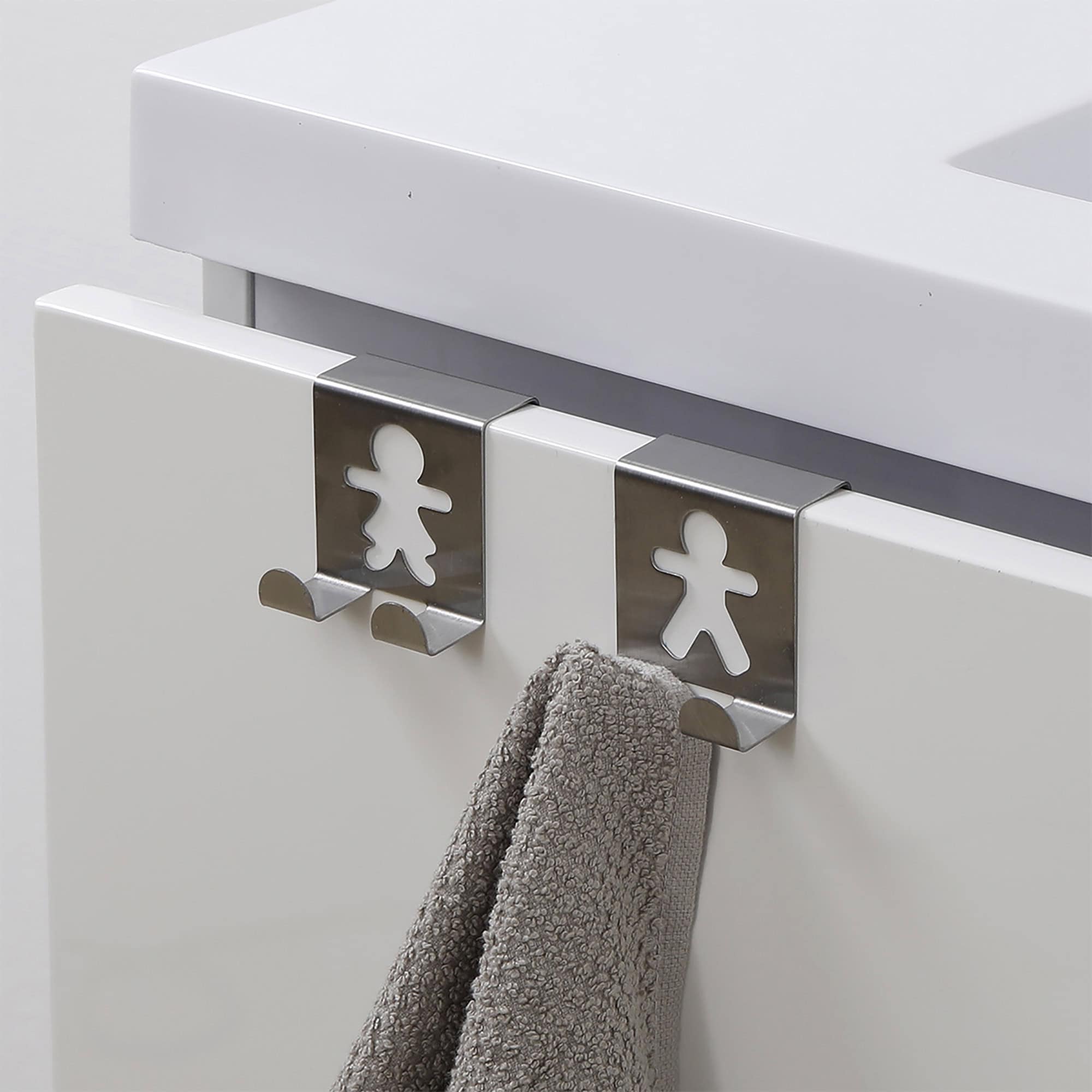 "Two stainless steel figure-shaped over-cabinet hooks on white drawer with gray towel hanging from one"