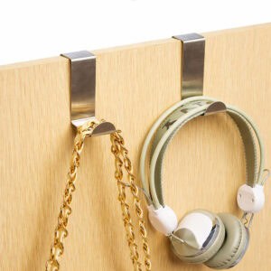 "Two stainless steel hooks on wood door holding a gold chain necklace and green headphones"