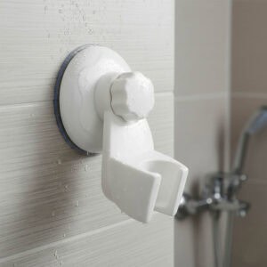 "Close-up of wet white suction shower head bracket mounted on tile wall"