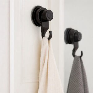 Two black suction cup hooks on a white door holding cream and gray waffle-weave towels