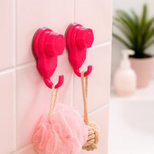Two hot pink suction cup hooks on pink tiles holding a pink bath loofah and natural rope loofah