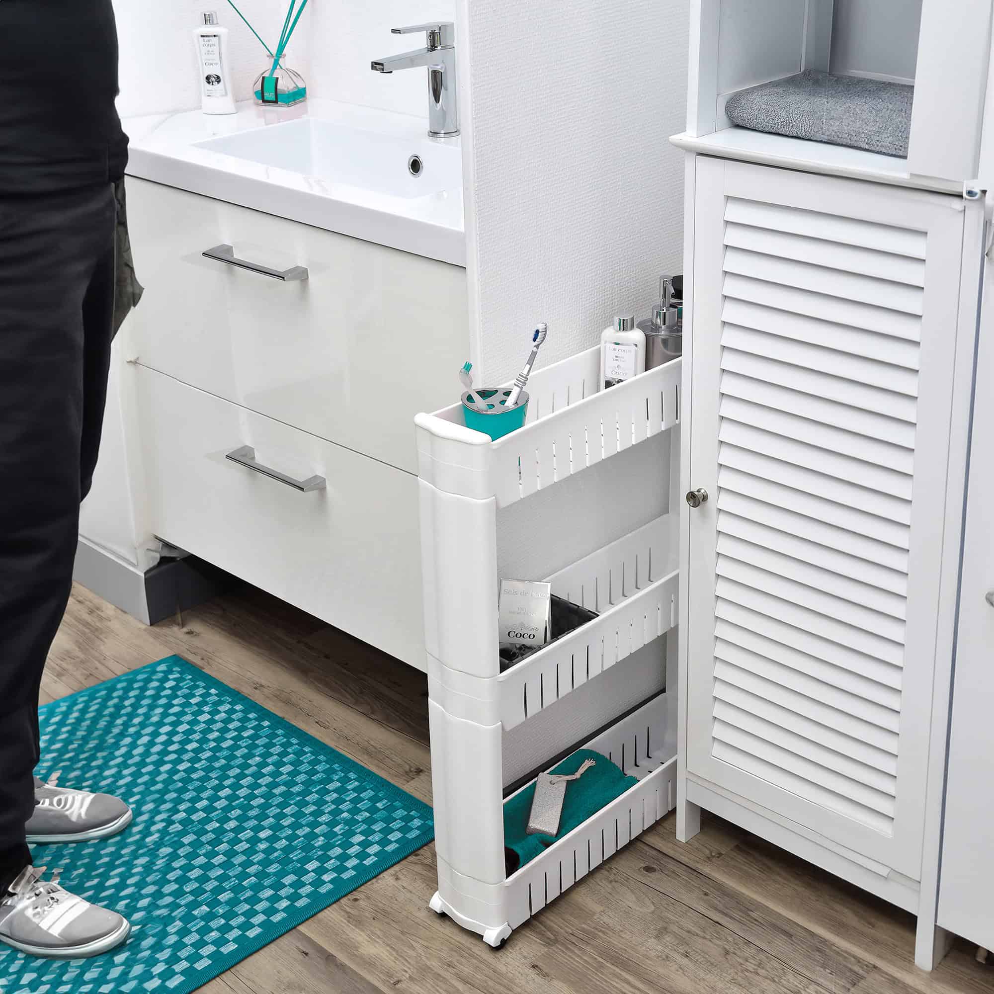 White 3-tier slim rolling cart holding toiletries, tucked between a bathroom vanity and storage cabinet
