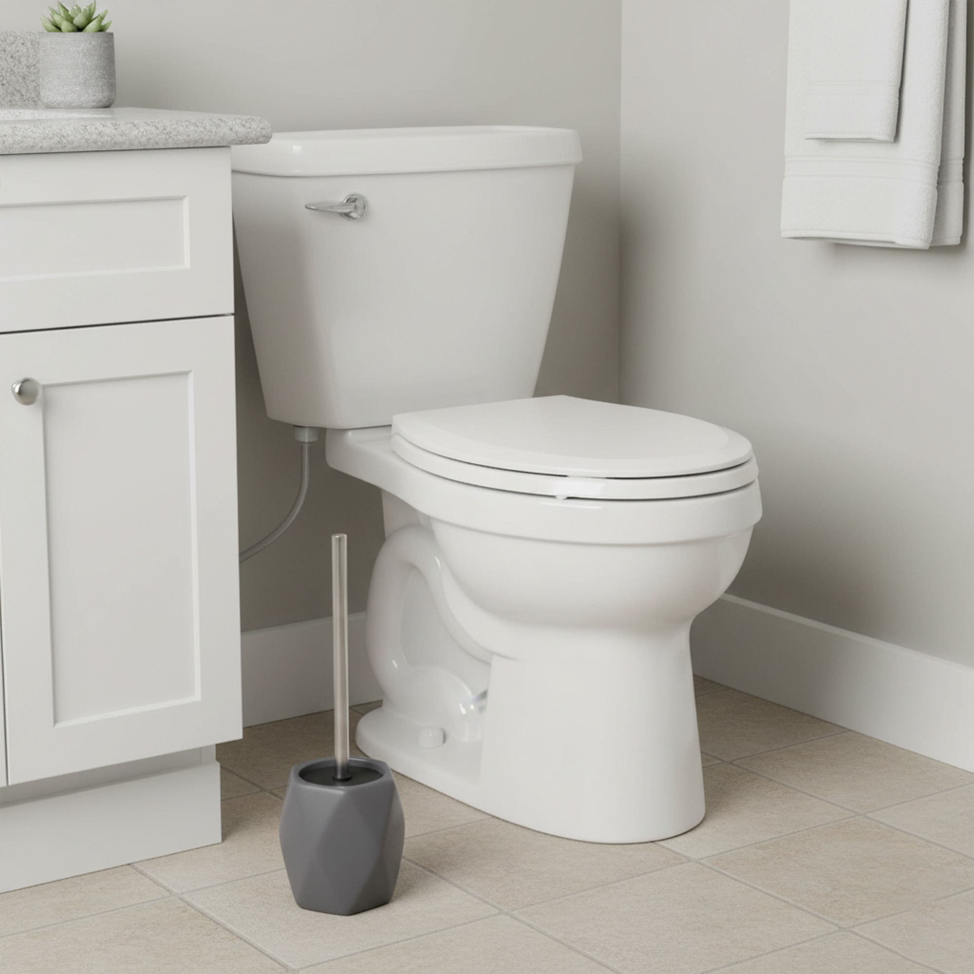 Gray diamond-shaped stoneware toilet brush with stainless steel handle beside white toilet in modern bathroom