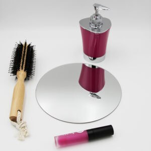 "Single round frameless mirror lying flat beside a hairbrush and cosmetics"