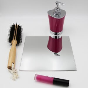 "Single square frameless mirror lying flat beside a hairbrush and cosmetics"