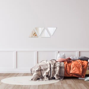 "Four small triangle mirrors in zigzag row on wall above a children's bedroom bed"