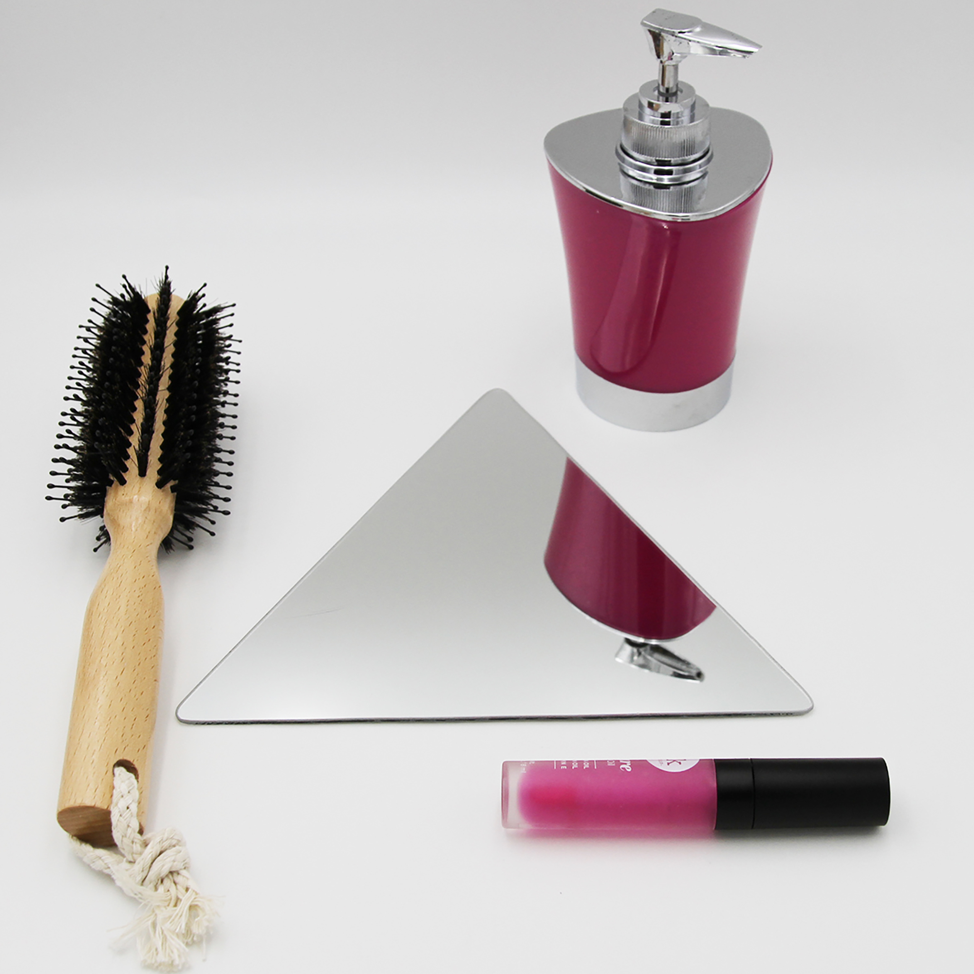 "Single triangle frameless mirror lying flat beside a hairbrush and cosmetics"