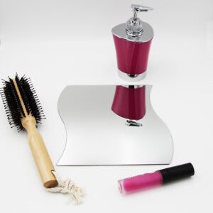 "Single wave-shaped frameless mirror lying flat beside a hairbrush and cosmetics"