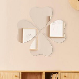 "Four heart-shaped mirrors arranged in a four-leaf clover pattern on a beige wall above a wooden sideboard"