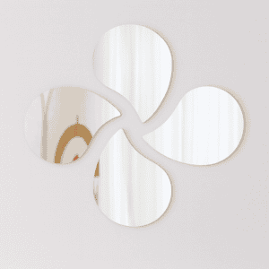 "Four teardrop-shaped mirrors arranged in a pinwheel pattern on a light grey wall"