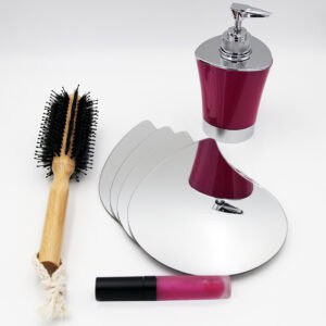 "Four stacked teardrop-shaped frameless mirrors lying flat beside a hairbrush and cosmetics"