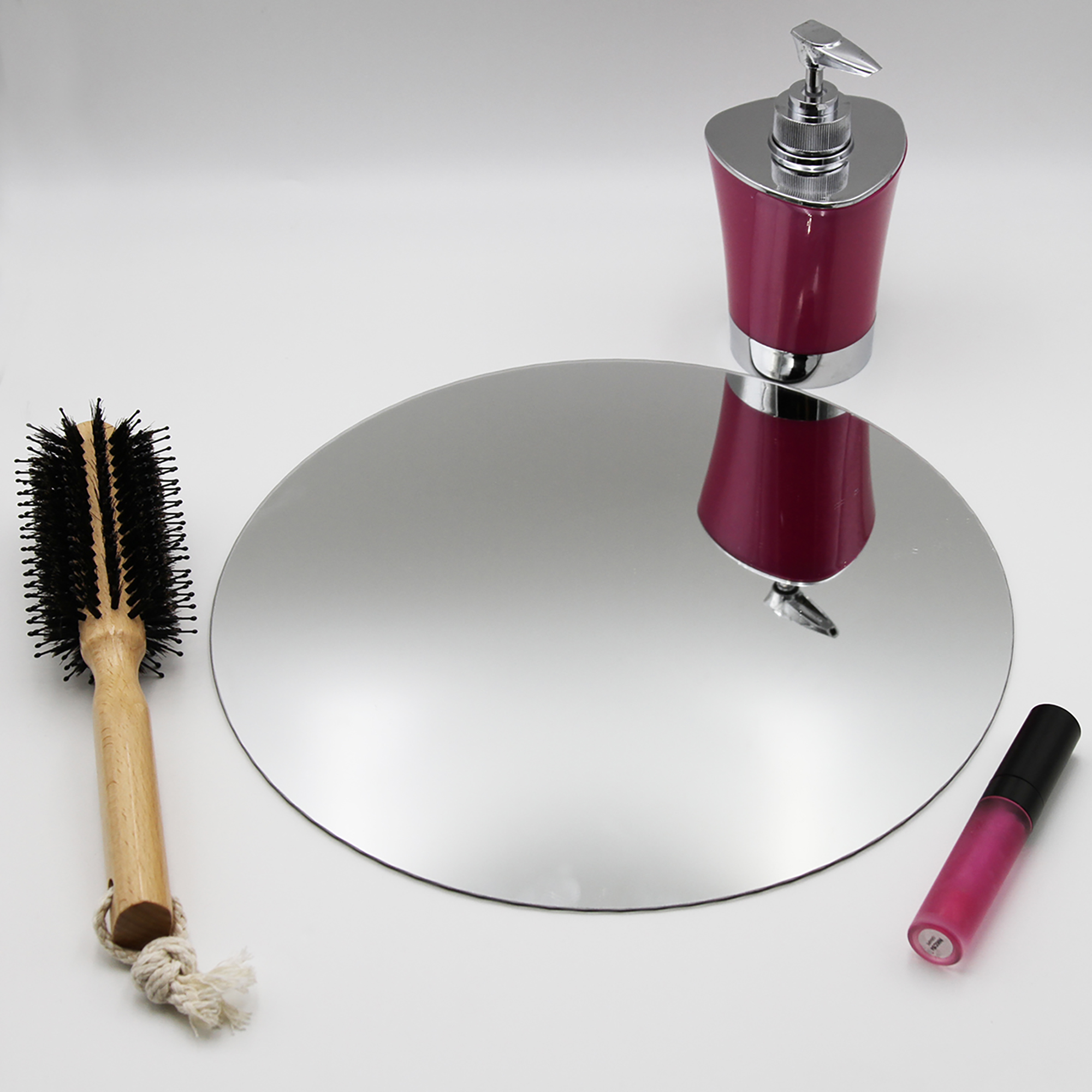 "Single large round frameless mirror lying flat beside a hairbrush and cosmetics"