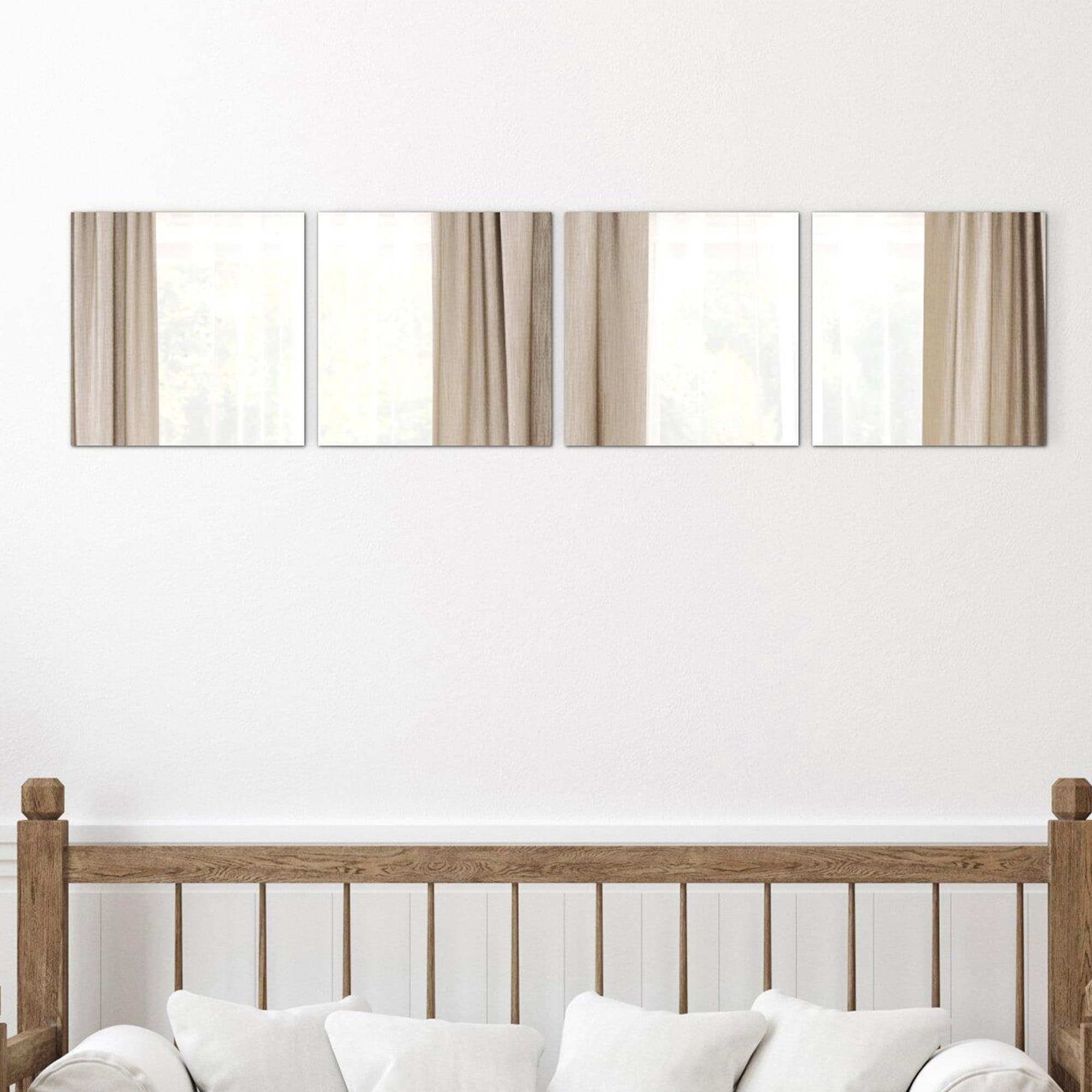 "Four large square frameless mirrors in horizontal row above a wooden bed headboard in a bedroom"