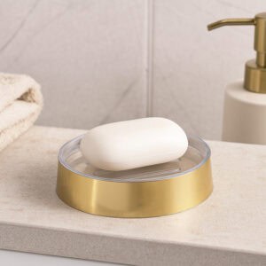 Gold soap dish with bar soap on textured vanity surface