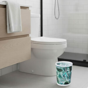 Tropical leaf print waste basket beside toilet in bathroom