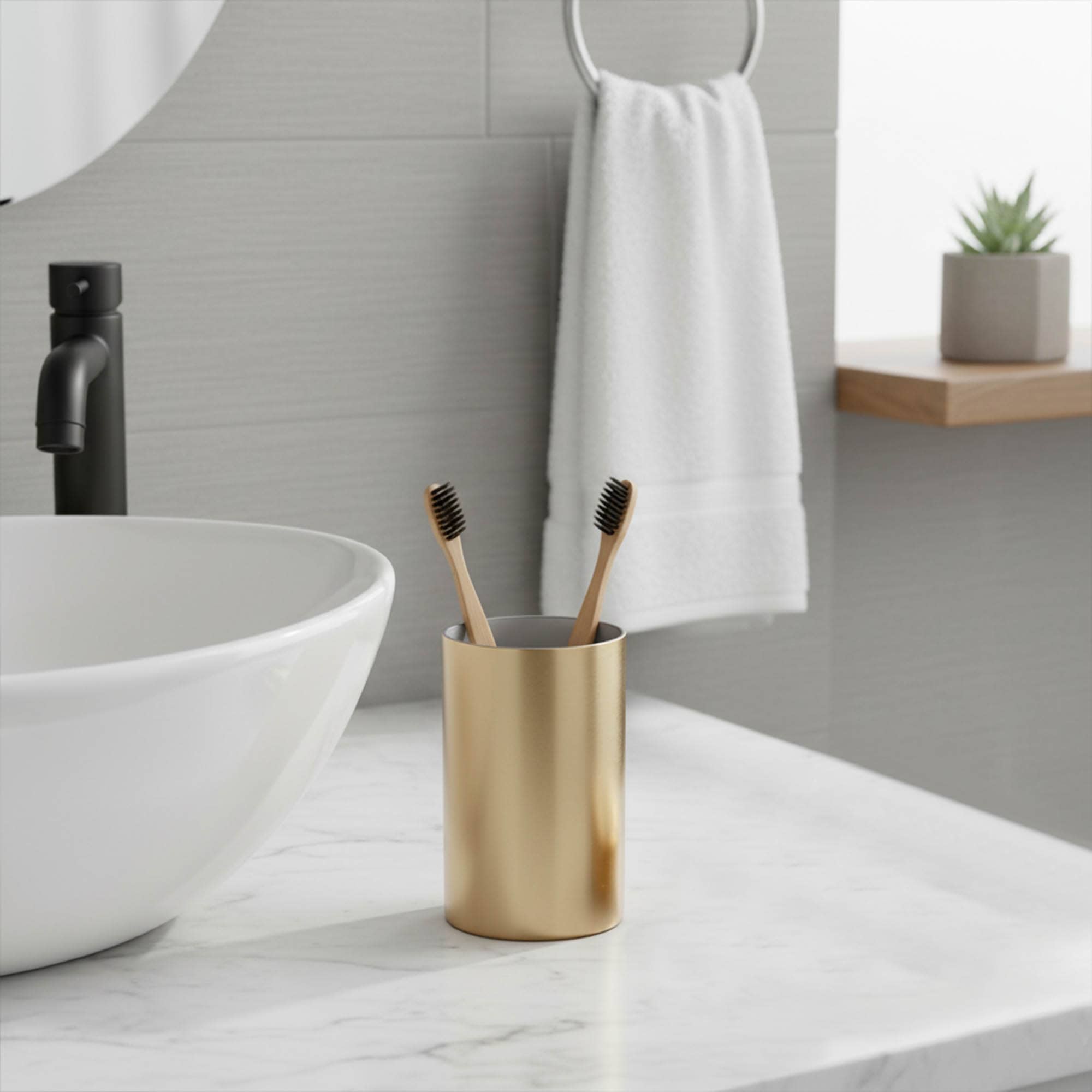 “Brushed gold tumbler holding toothbrushes on bathroom counter”