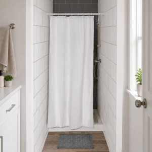 White half size shower curtain closing a narrow tiled shower stall in a small bright bathroom