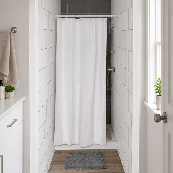 White half size shower curtain closing a narrow tiled shower stall in a small bright bathroom