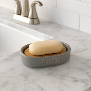 Grey soap dish with bamboo insert near sink on marble counter