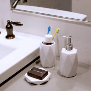 White bathroom accessories set on sink counter with toothbrush holder and soap dish