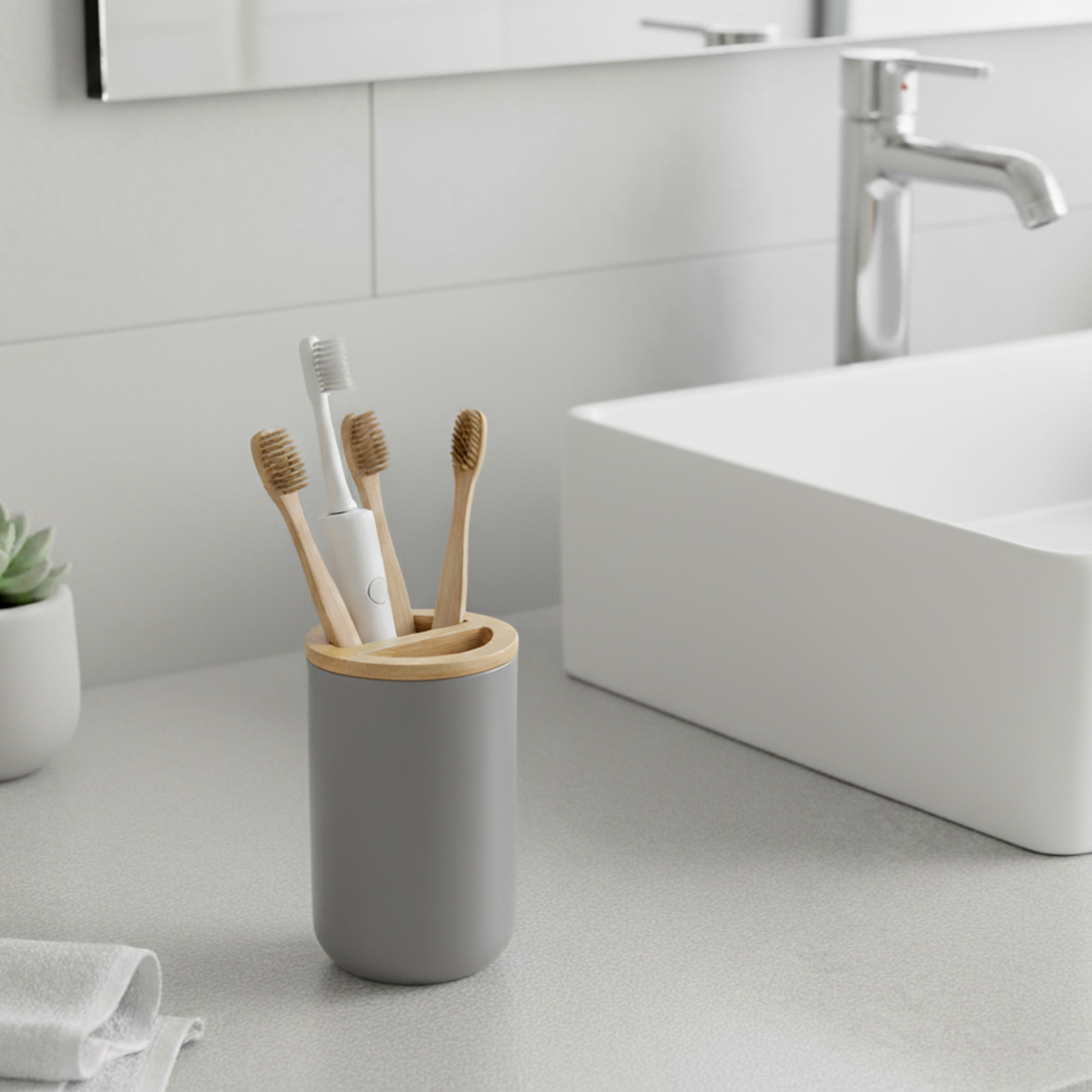 Gray toothbrush holder with bamboo top on modern bathroom sink