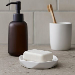 Soap dish with bar soap next to dispenser and tumbler