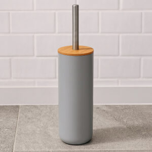 Gray toilet brush holder with bamboo lid and stainless steel handle against white subway tile wall