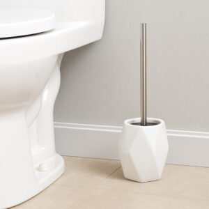 White diamond-shaped stoneware toilet brush holder beside white toilet against beige wall