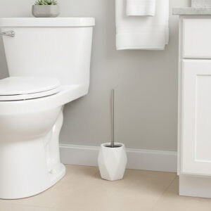 White diamond-shaped stoneware toilet brush with stainless steel handle beside white toilet in modern bathroom