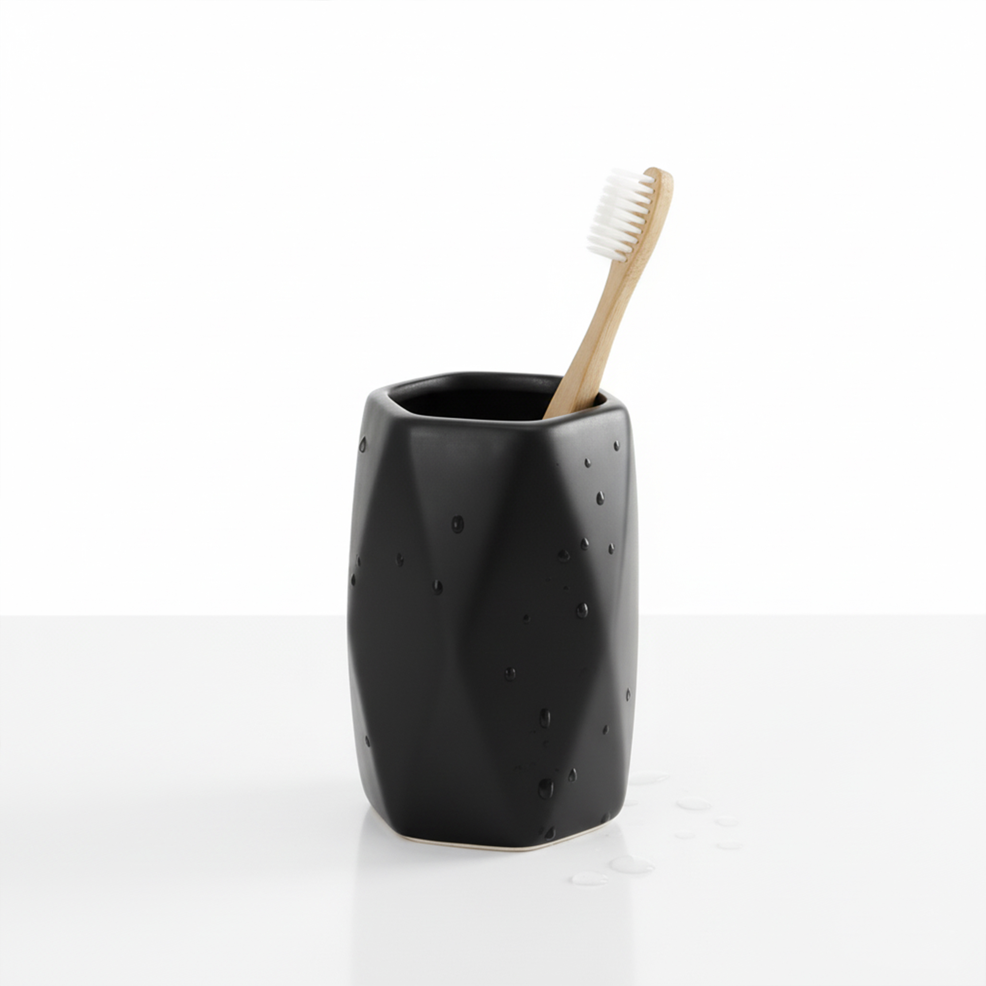 Matte black stoneware bathroom tumbler with toothbrush on white background