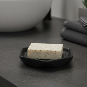 Black soap dish holding bar soap on dark countertop