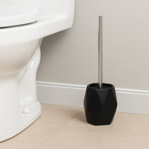 Black diamond-shaped stoneware toilet brush holder with stainless steel handle beside white toilet