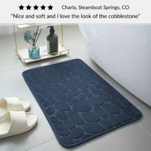 Navy blue memory foam mat with raised pebble design placed near bathtub with five-star customer review text overlay
