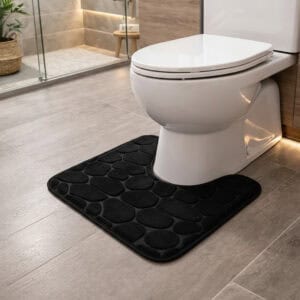 Black pebble-embossed memory foam contour mat around toilet, side-angle view in modern bathroom