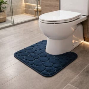 Navy blue pebble-embossed memory foam contour mat around toilet, side-angle view in modern bathroom