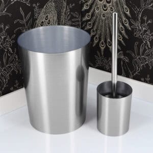 Brushed aluminum toilet brush holder and matching waste bin against black peacock feather wallpaper
