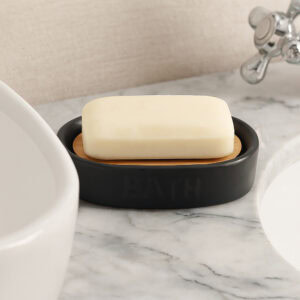 Soap dish with bamboo insert beside sink on marble counter