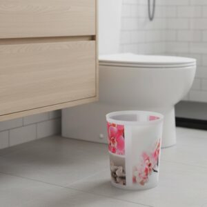 Orchid print waste basket beside toilet in modern bathroom