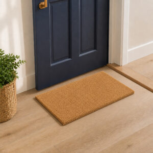 Coir entrance mat on light hardwood floor inside navy front door