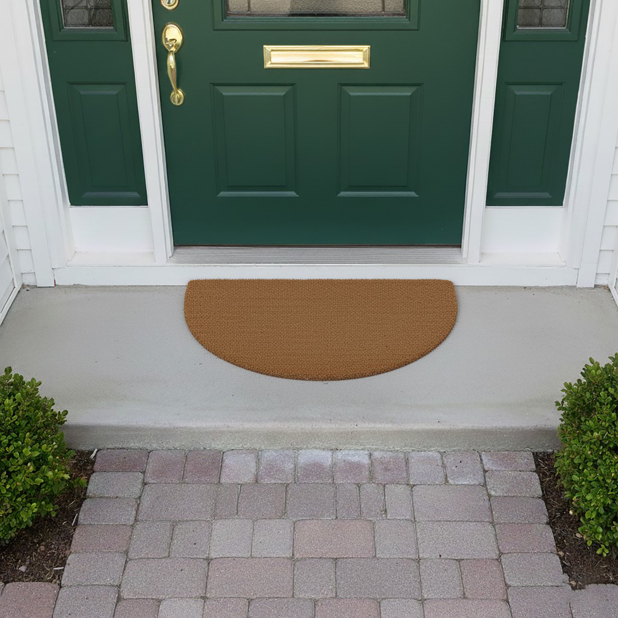 Half-moon natural coir doormat placed at green front door on porch paving