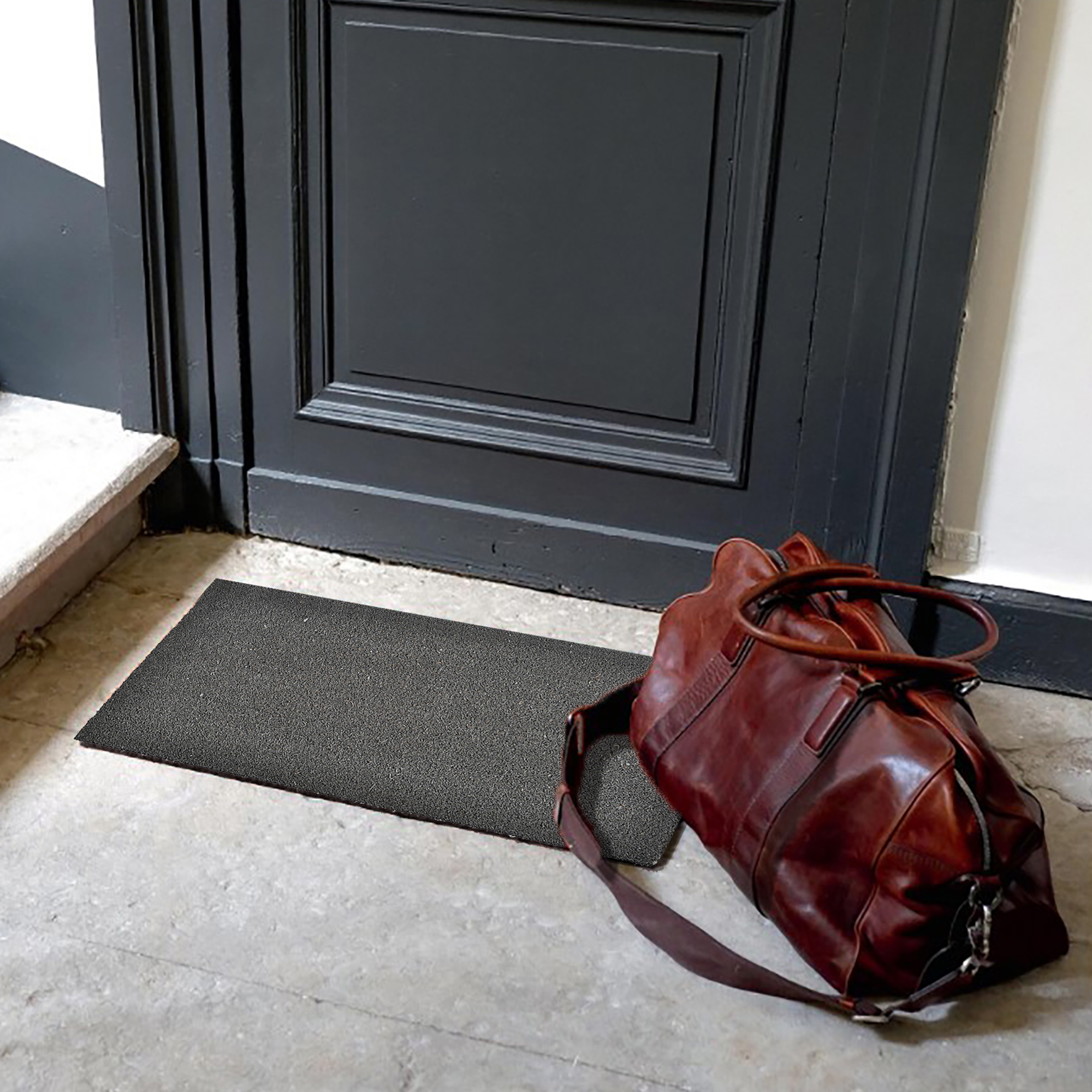 “Grey coir doormat at indoor doorway beside leather travel bag”