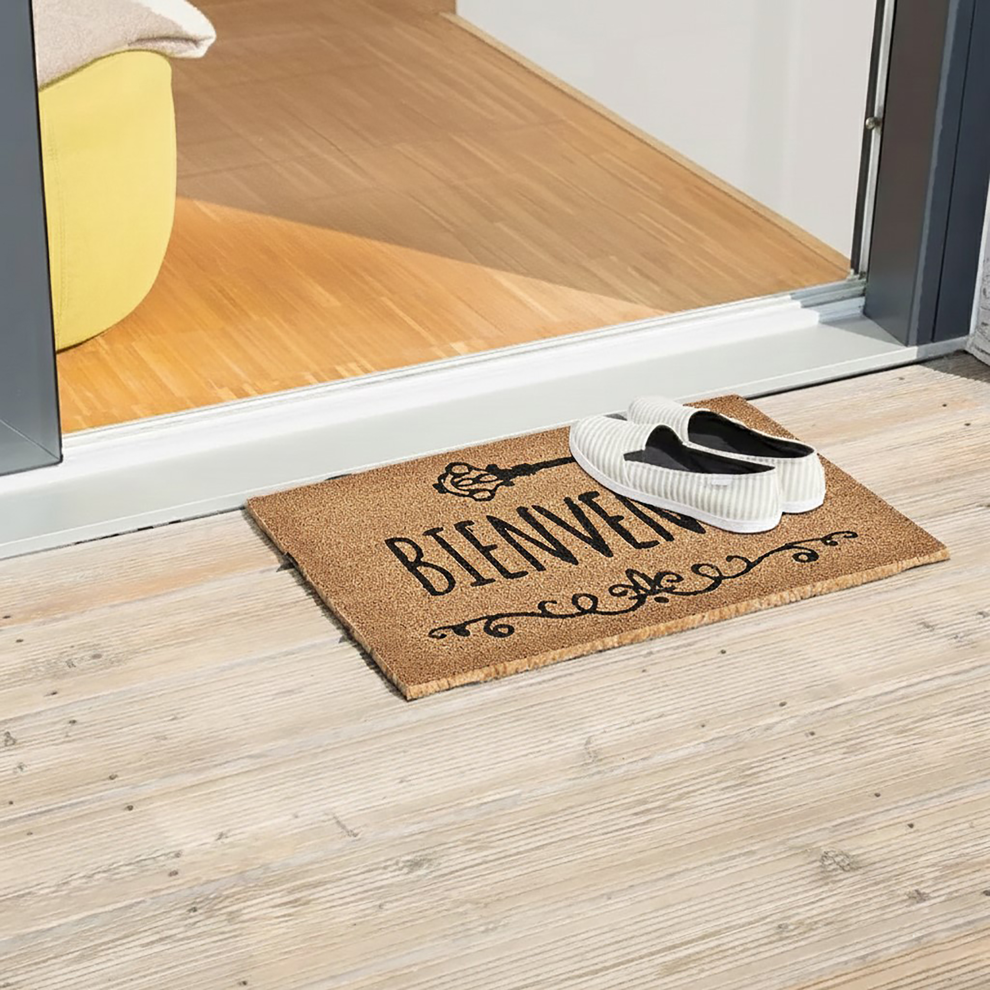 Bienvenue coir doormat placed at sliding door on wood deck with shoes
