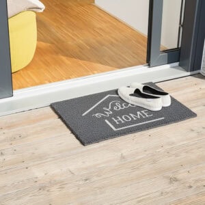 Grey welcome home doormat on wood deck with slip-on shoes at doorway