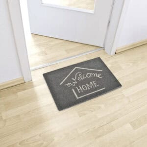 Grey welcome home doormat placed inside entry on light wood flooring