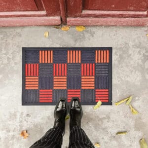 Overhead view of checkered doormat at entrance with shoes standing on mat