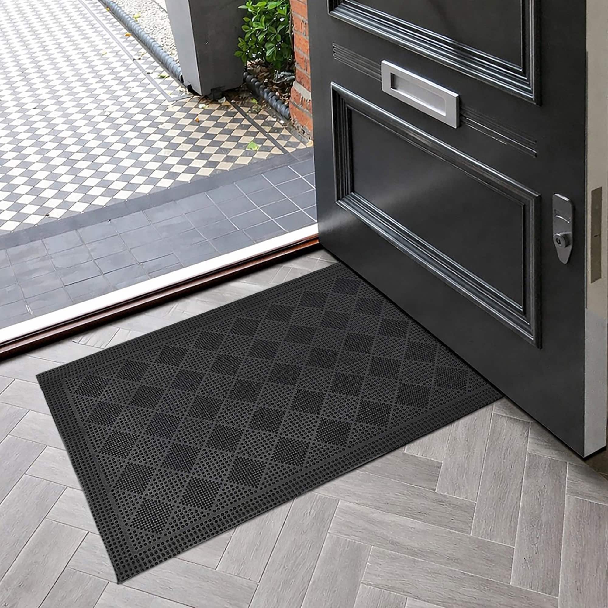 Black rubber entry mat with checkerboard pattern near open door
