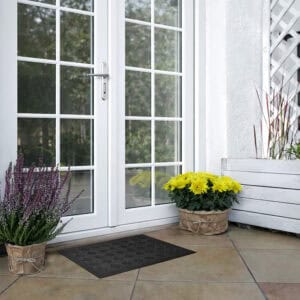 Small black rubber door mat on patio in front of glass door