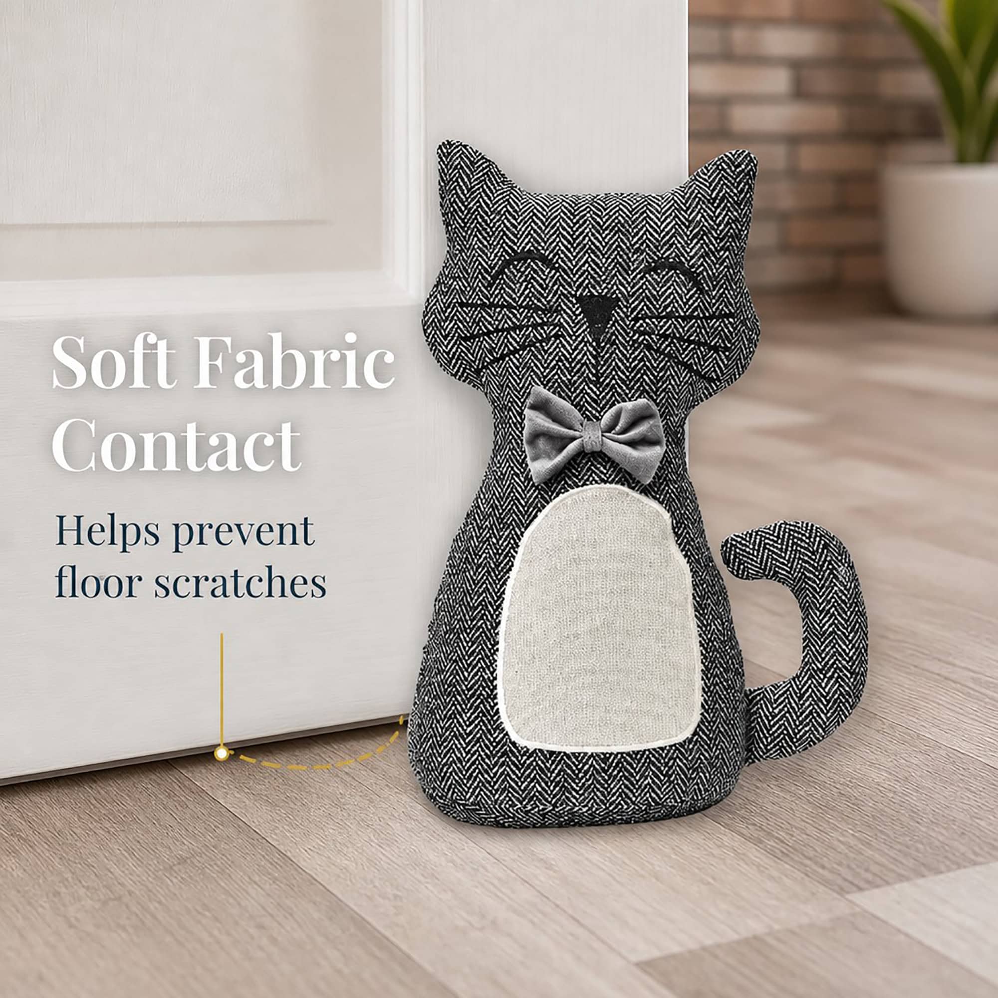 Charcoal cat door stopper against a white door with a dashed line pointing to its base. On-image text: "Soft Fabric Contact," "Helps prevent floor scratches."